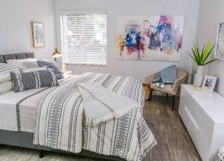 ViveLA Violet on Virgil; Spacious bed overlooking a wide dresser next to an armchair at Violet on Virgil