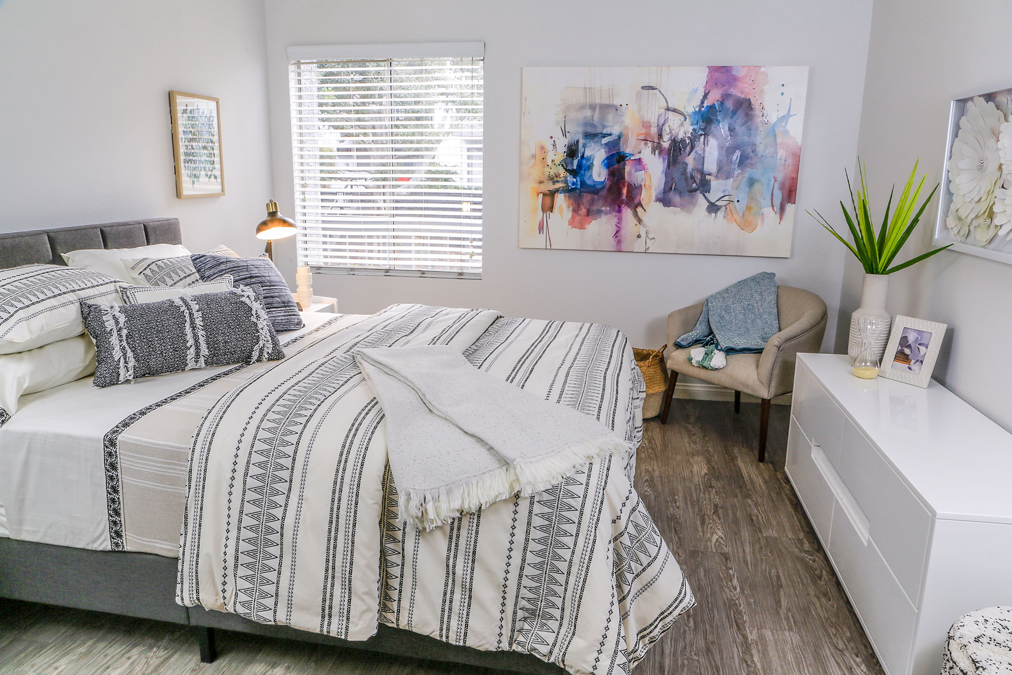 ViveLA Violet on Virgil; Spacious bed overlooking a wide dresser next to an armchair at Violet on Virgil