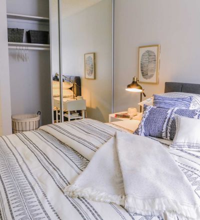 ViveLA Violet on Virgil; Bed with tufted headboard, pillows and duvets next to a mirror slider closet