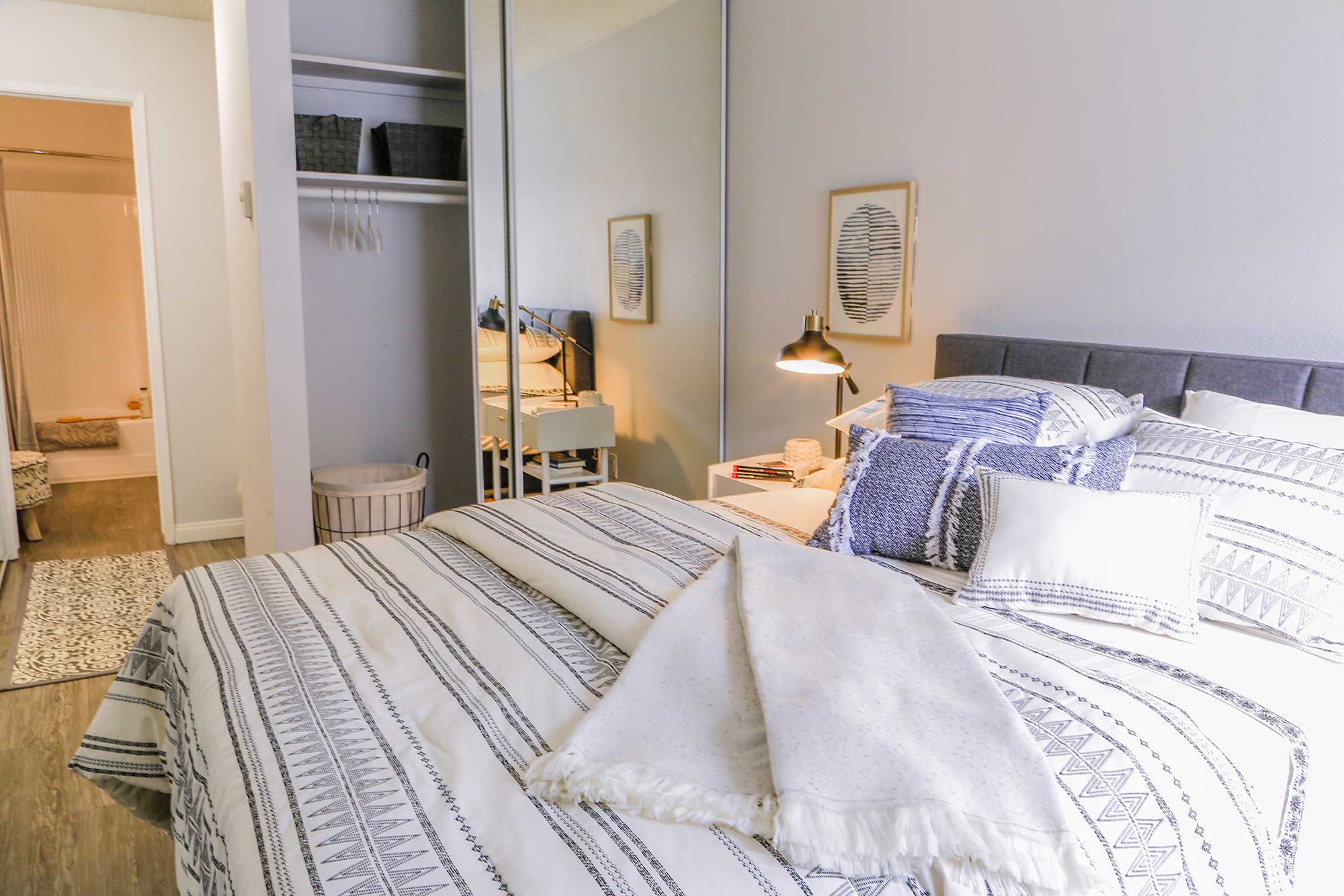 ViveLA Violet on Virgil; Bed with tufted headboard, pillows and duvets next to a mirror slider closet