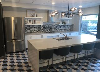 Violet on Virgil; large kitchen area with a wide sink countertop and bar chairs overlooking the stove countertop next to a geometric tiled-wall