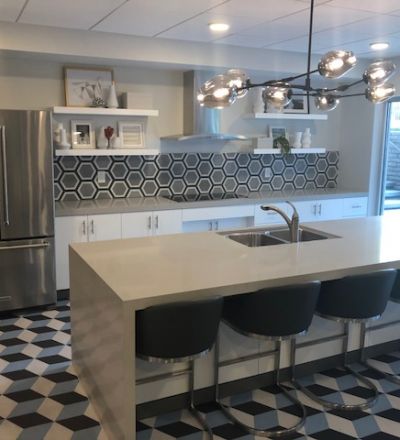 Violet on Virgil; large kitchen area with a wide sink countertop and bar chairs overlooking the stove countertop next to a geometric tiled-wall