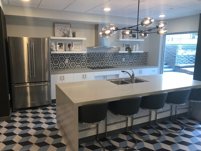Violet on Virgil; large kitchen area with a wide sink countertop and bar chairs overlooking the stove countertop next to a geometric tiled-wall