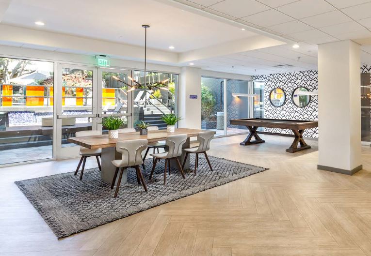 Communal space with table and chairs next to the pool table at Violet on Virgil Apartments