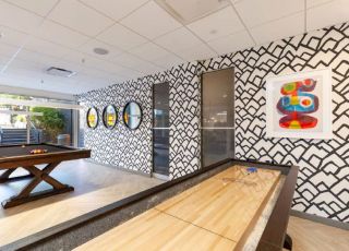 Shuffle board and pool table in the game room at Violet on Virgil Apartments