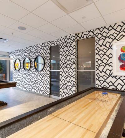 Shuffle board and pool table in the game room at Violet on Virgil Apartments