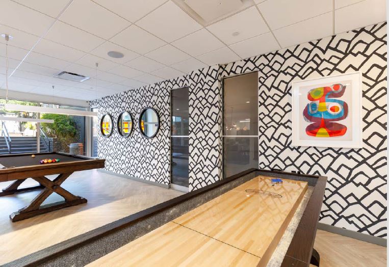 Shuffle board and pool table in the game room at Violet on Virgil Apartments