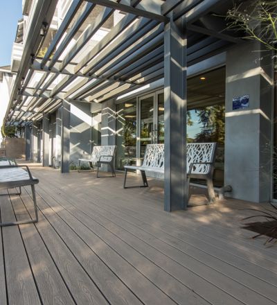 Violet on Virgil Apartments patio with a wooden deck and iron benches next to garden beds
