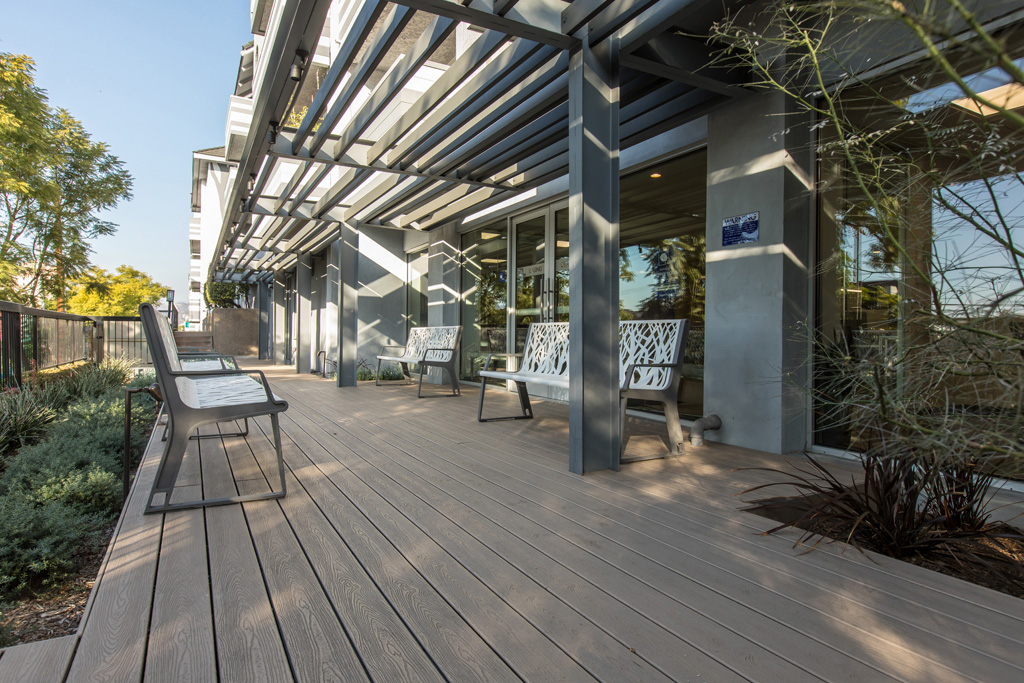 Violet on Virgil Apartments patio with a wooden deck and iron benches next to garden beds