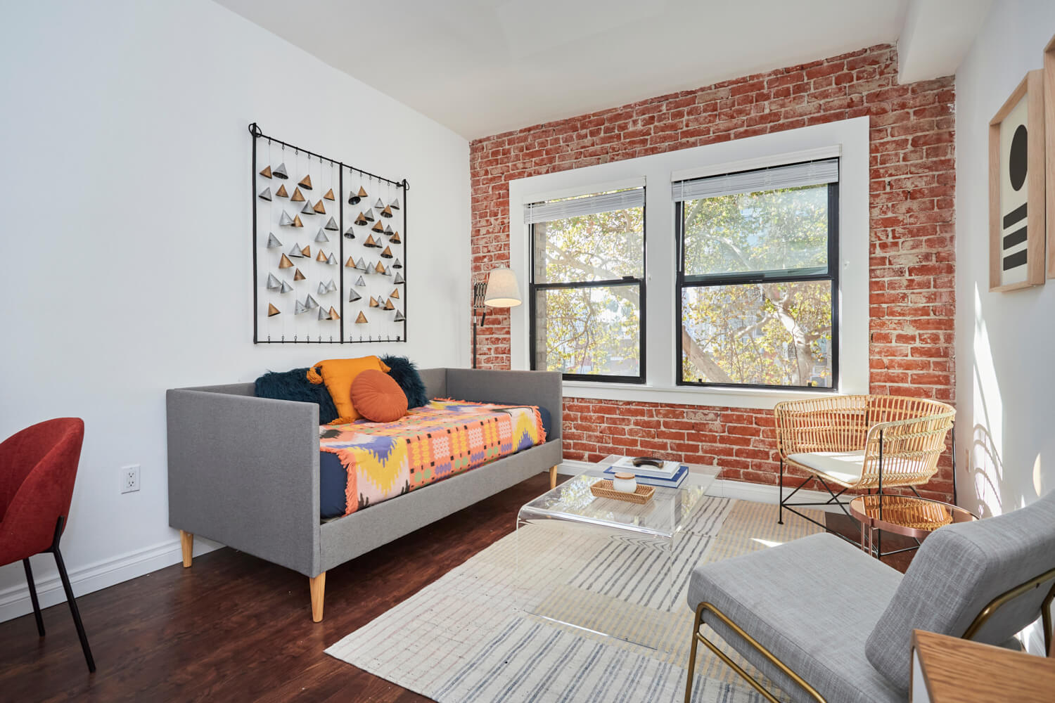 Exposed brick wall next to a sofa overlooking a glass coffee table and armchairs at The Gershwin Apartments living room area