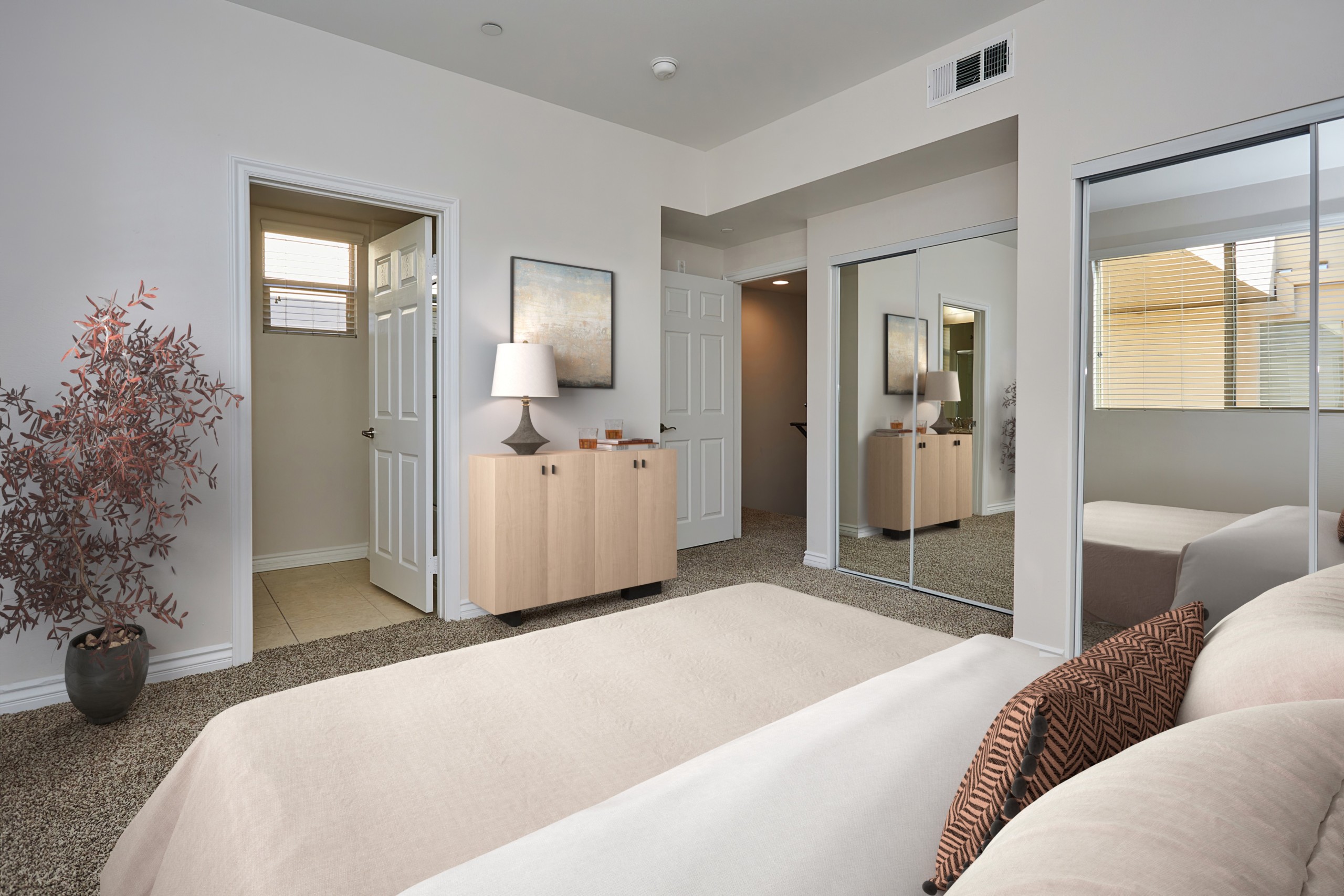 Spacious bed with pillows and comforters overlooking an en-suite bathroom