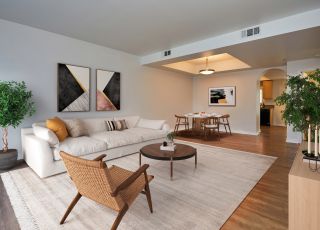 Large couch with pillows next to a coffee table and a woven armchair at the Magnolia Woods living room