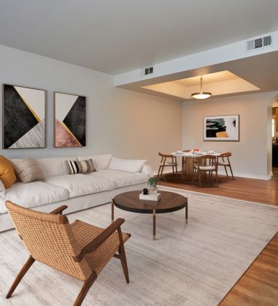 Large couch with pillows next to a coffee table and a woven armchair at the Magnolia Woods living room
