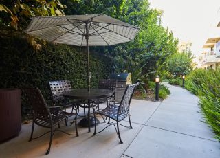 Table with an umbrella stand next to chairs amidst the lush greenery at Magnolia Woods