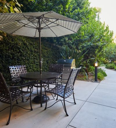 Table with an umbrella stand next to chairs amidst the lush greenery at Magnolia Woods
