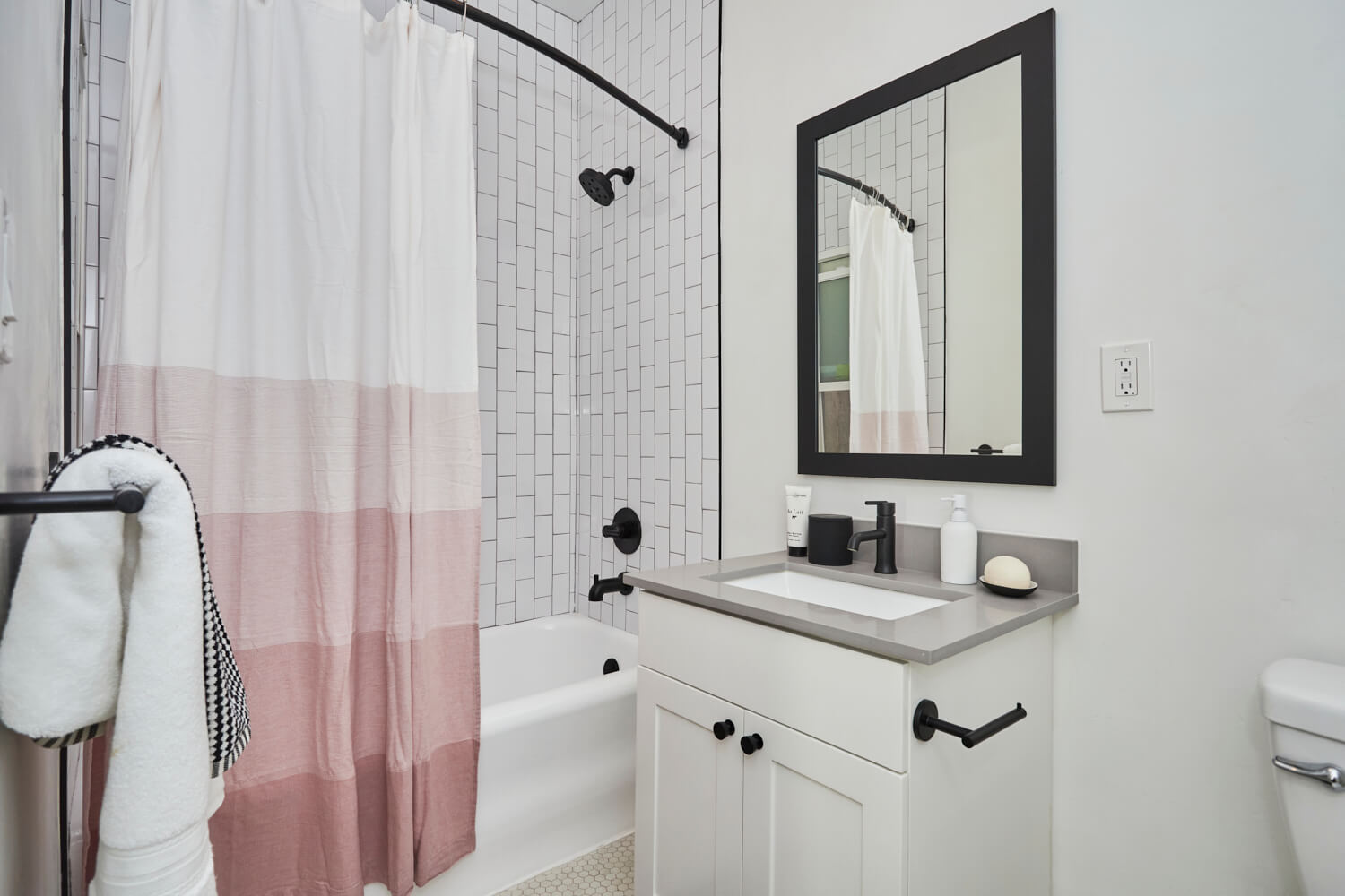 dark-framed wall mirror next to the bathroom countertop with cabinet beside the bathtub; Luxury Hollywood Rentals; boutique community apartments in Hollywood