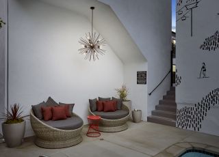 Woven egg chairs with cushion next to a red stool next to the staircase at Chloe on Curson