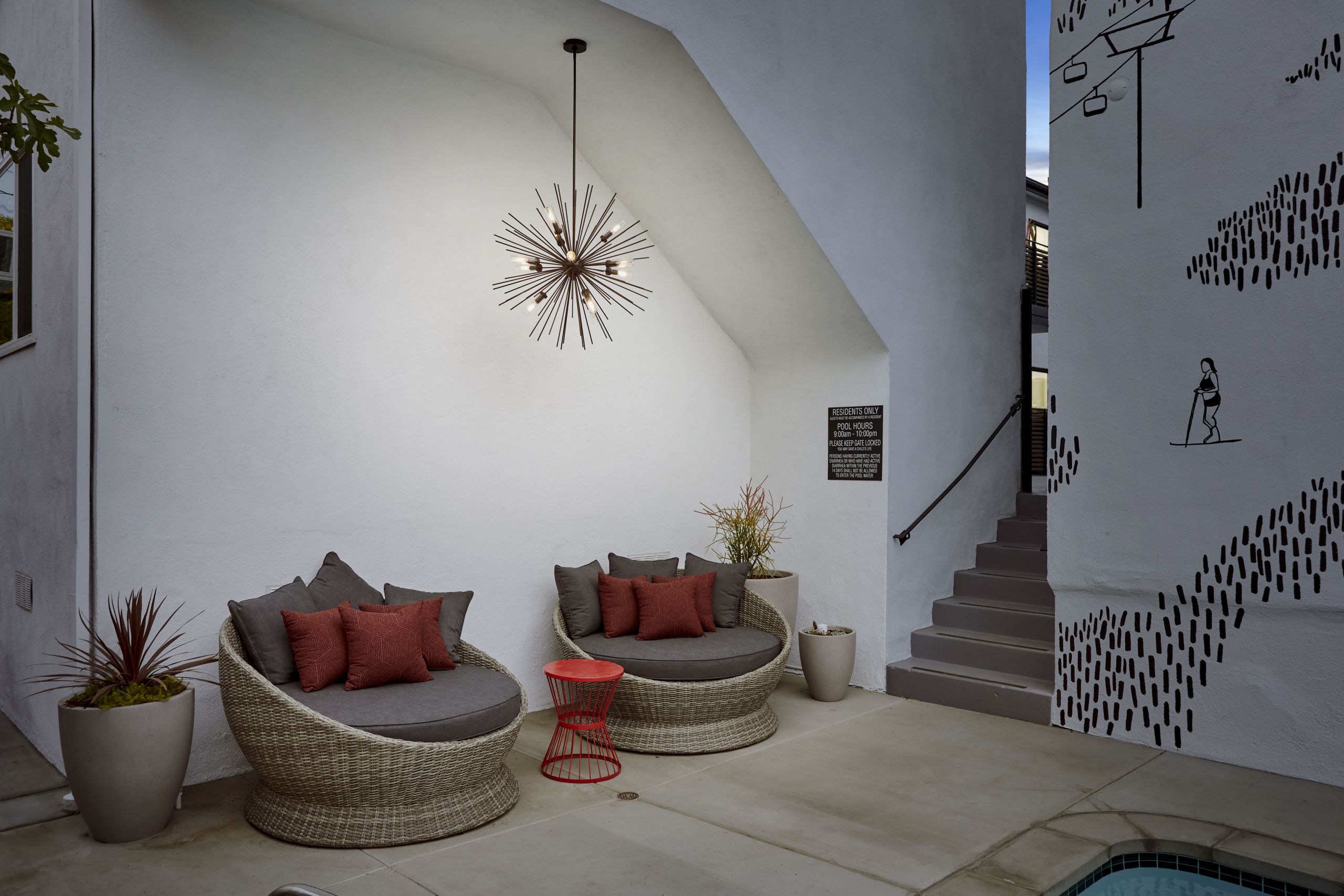 Woven egg chairs with cushion next to a red stool next to the staircase at Chloe on Curson