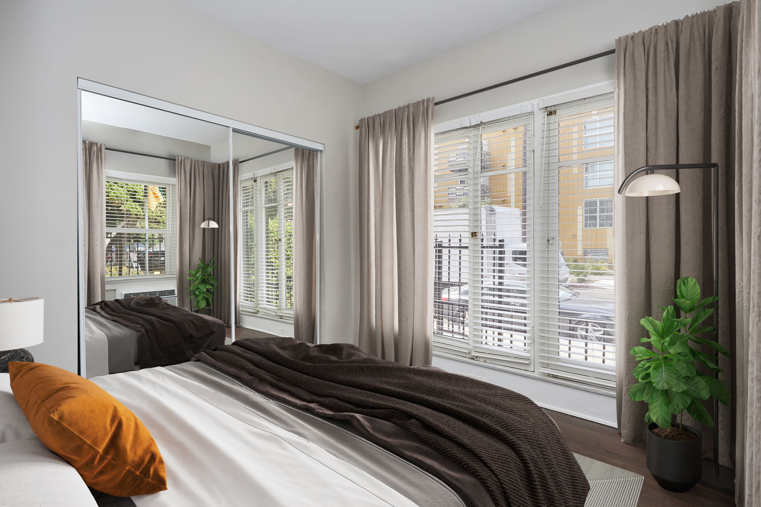 Spacious bed with comforters next to a mirror slider door closer overlooking a wide window; Luxury Hollywood Rentals; boutique community apartments in Hollywood