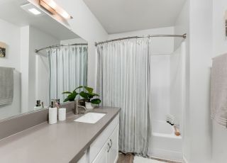 The Violet On Virgil Apartments rental apartments in LA; A modern bathroom featuring a sleek shower, a stylish sink, and a large mirror.