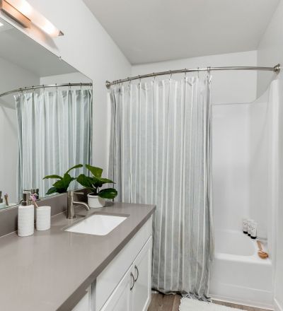 The Violet On Virgil Apartments rental apartments in LA; A modern bathroom featuring a sleek shower, a stylish sink, and a large mirror.