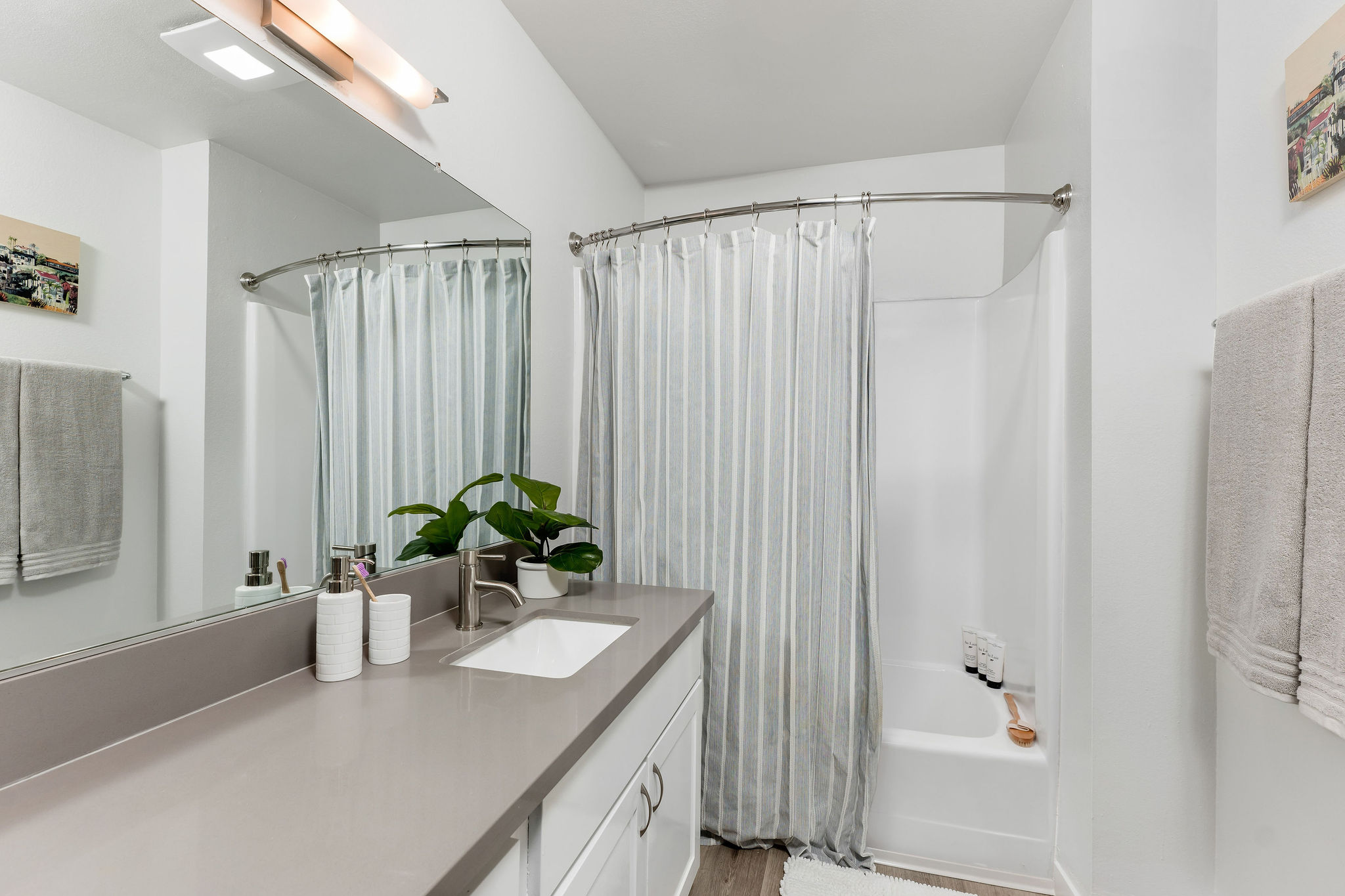 The Violet On Virgil Apartments rental apartments in LA; A modern bathroom featuring a sleek shower, a stylish sink, and a large mirror.